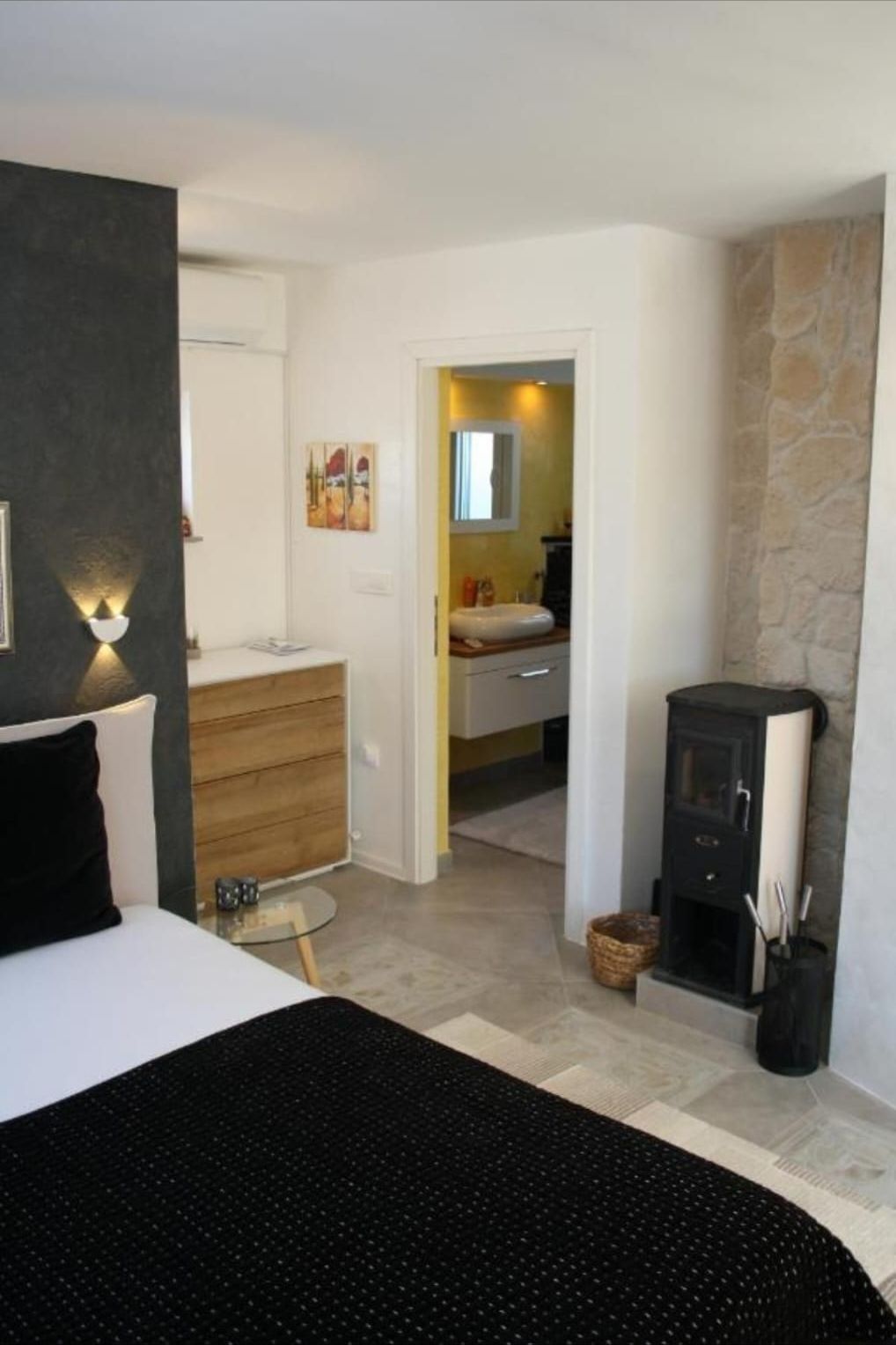 Schlafzimmer mit Kaminofen und Blick ins Bad